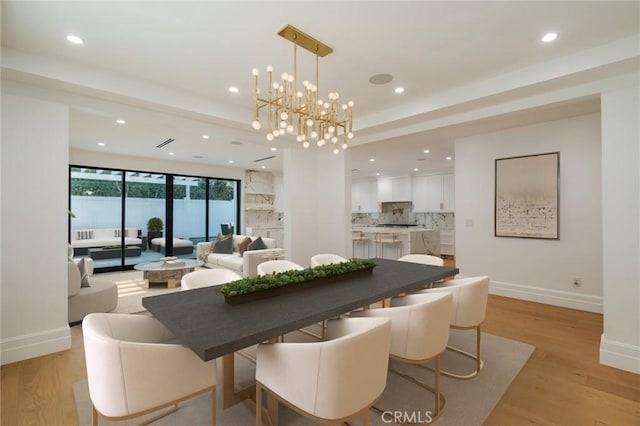 dining space with light wood-type flooring and an inviting chandelier