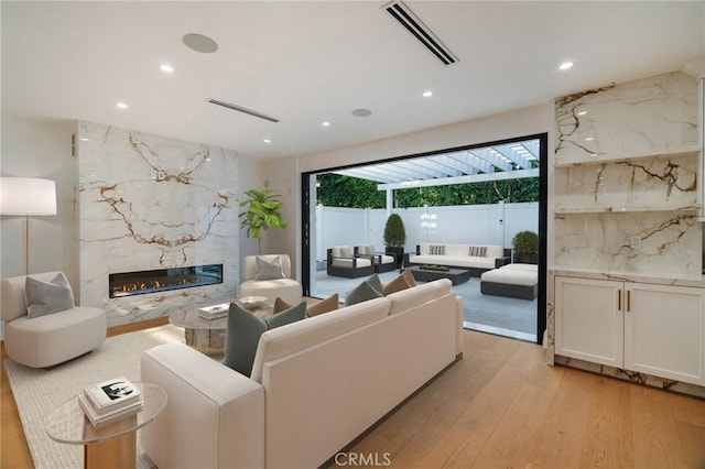 living room with light hardwood / wood-style floors and a high end fireplace