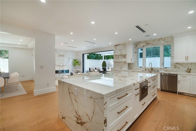 kitchen with a center island, stainless steel appliances, light hardwood / wood-style flooring, and a wealth of natural light