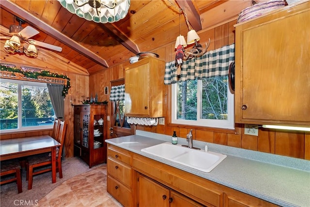 kitchen featuring pendant lighting, lofted ceiling with beams, sink, and wooden walls