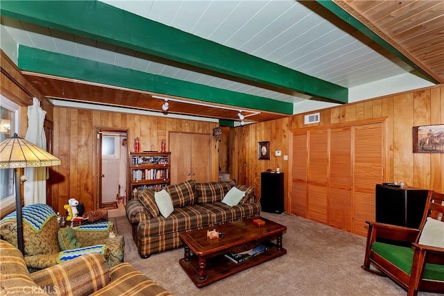 living room with beamed ceiling, wood walls, and light colored carpet