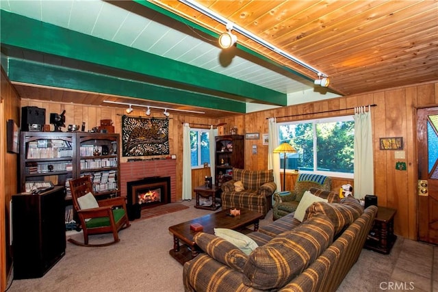 carpeted living room with wood walls, a fireplace, rail lighting, and wooden ceiling