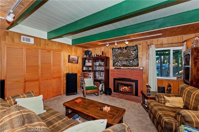 living room with carpet, rail lighting, wooden walls, and a brick fireplace