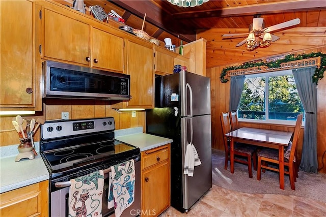 kitchen with wood walls, ceiling fan, appliances with stainless steel finishes, beamed ceiling, and wood ceiling