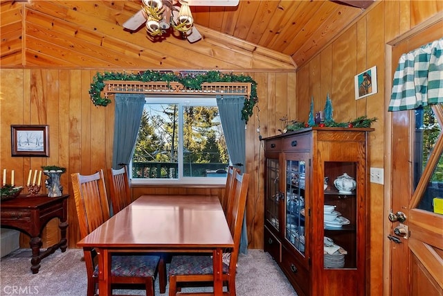 dining area featuring wood walls, carpet, wooden ceiling, and vaulted ceiling