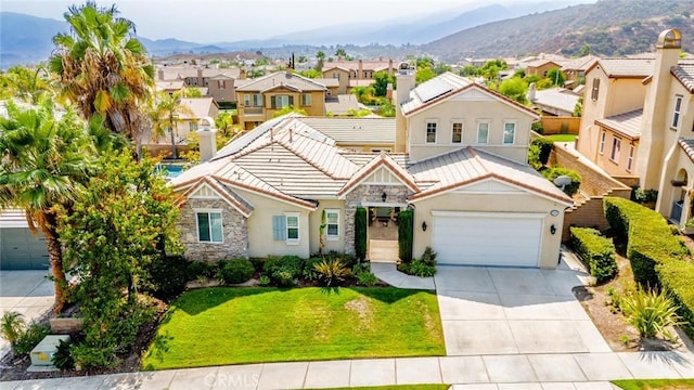 view of front of house featuring a mountain view, a front yard, and a garage