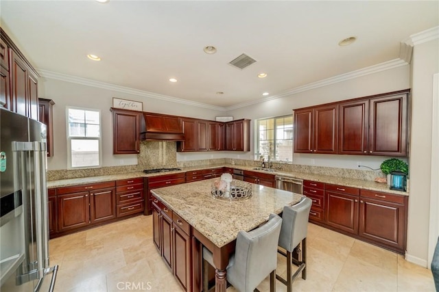 kitchen with a wealth of natural light, a center island, crown molding, and appliances with stainless steel finishes