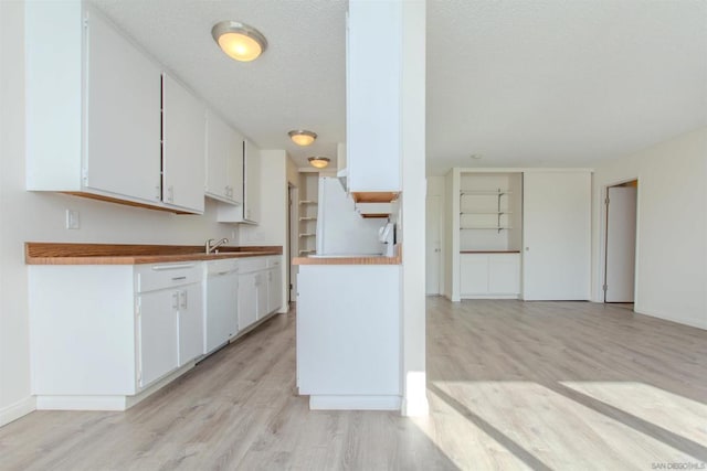 kitchen with white cabinets, a textured ceiling, and light wood-type flooring