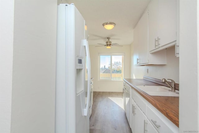 kitchen with white appliances, light hardwood / wood-style floors, white cabinetry, and sink