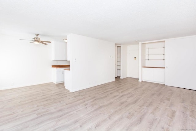 unfurnished living room with ceiling fan, light hardwood / wood-style floors, and a textured ceiling