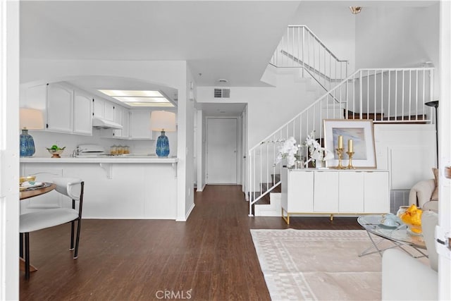 kitchen featuring a kitchen bar, kitchen peninsula, white cabinetry, and dark hardwood / wood-style floors