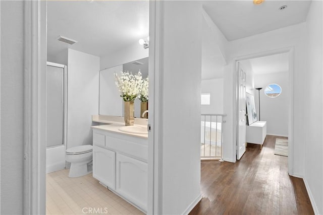 full bathroom featuring hardwood / wood-style flooring, vanity, toilet, and bath / shower combo with glass door