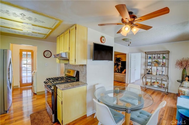 kitchen featuring under cabinet range hood, ceiling fan, light wood-style flooring, and stainless steel appliances