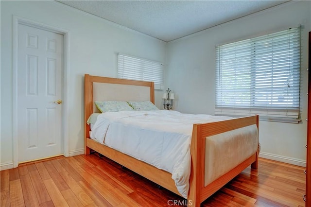 bedroom featuring crown molding, a textured ceiling, and light hardwood / wood-style flooring