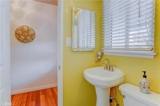 bathroom featuring baseboards, toilet, a sink, and wood finished floors