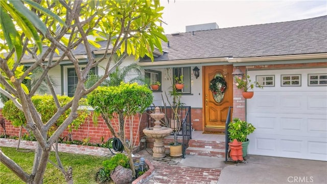 property entrance with brick siding, a garage, roof with shingles, and stucco siding
