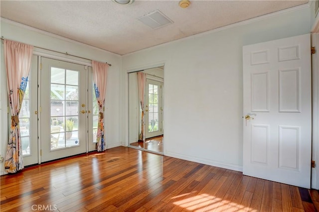spare room featuring hardwood / wood-style floors, ornamental molding, baseboards, and a textured ceiling