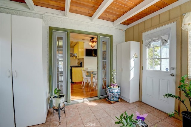 doorway to outside with ceiling fan, beam ceiling, light tile patterned floors, and wooden ceiling