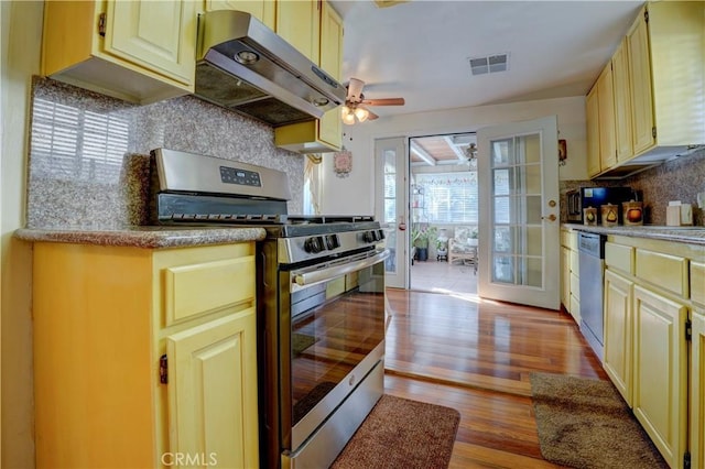 kitchen featuring exhaust hood, french doors, ceiling fan, light wood-type flooring, and stainless steel appliances