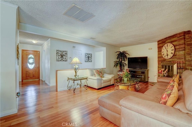 living room with a textured ceiling, baseboards, and wood finished floors
