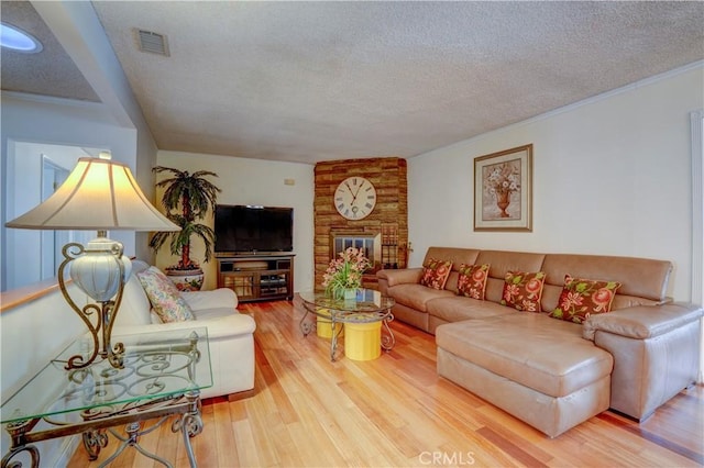 living room with hardwood / wood-style floors, a fireplace, ornamental molding, and a textured ceiling