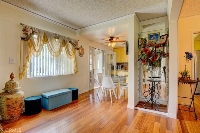 dining room with a textured ceiling, light hardwood / wood-style floors, ceiling fan, and ornamental molding