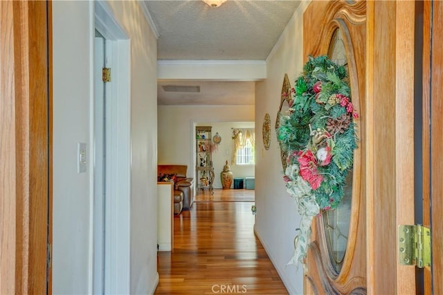 hall featuring visible vents, wood finished floors, and a textured ceiling