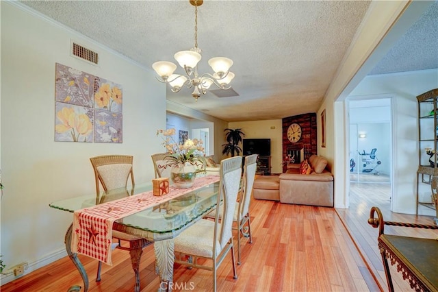 dining area with hardwood / wood-style floors, ornamental molding, a textured ceiling, and an inviting chandelier