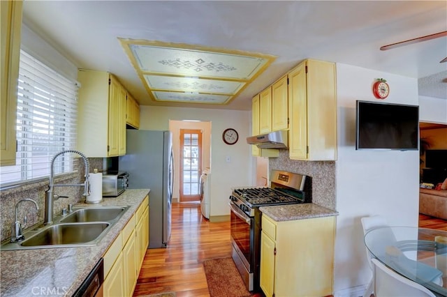 kitchen featuring appliances with stainless steel finishes, backsplash, sink, light hardwood / wood-style flooring, and washer / dryer