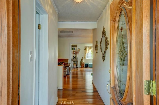 hall featuring hardwood / wood-style floors, crown molding, and a textured ceiling