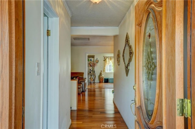 hallway with visible vents, crown molding, wood finished floors, and a textured ceiling