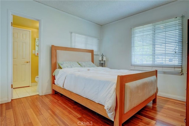 bedroom featuring baseboards, a textured ceiling, wood finished floors, and crown molding