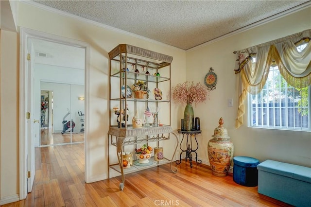 interior space with hardwood / wood-style floors, a textured ceiling, and crown molding