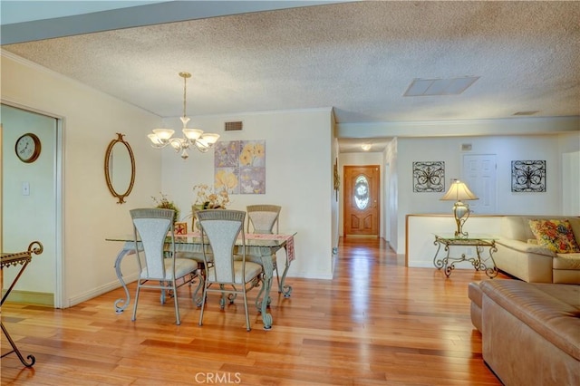 dining space with wood-type flooring, a textured ceiling, and a notable chandelier