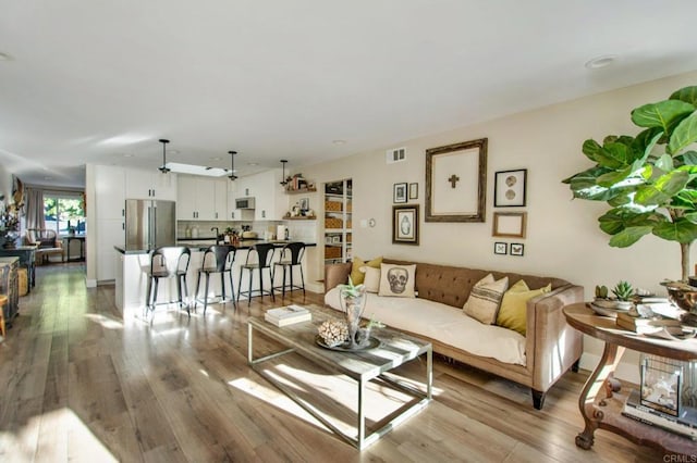 living room with ceiling fan and light hardwood / wood-style flooring