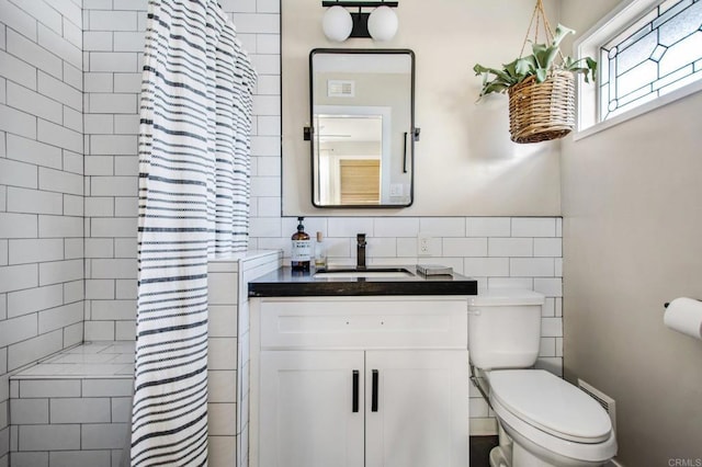 bathroom with tile walls, a shower with shower curtain, vanity, and toilet