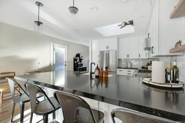 kitchen with white cabinets, decorative backsplash, a skylight, hanging light fixtures, and high end fridge