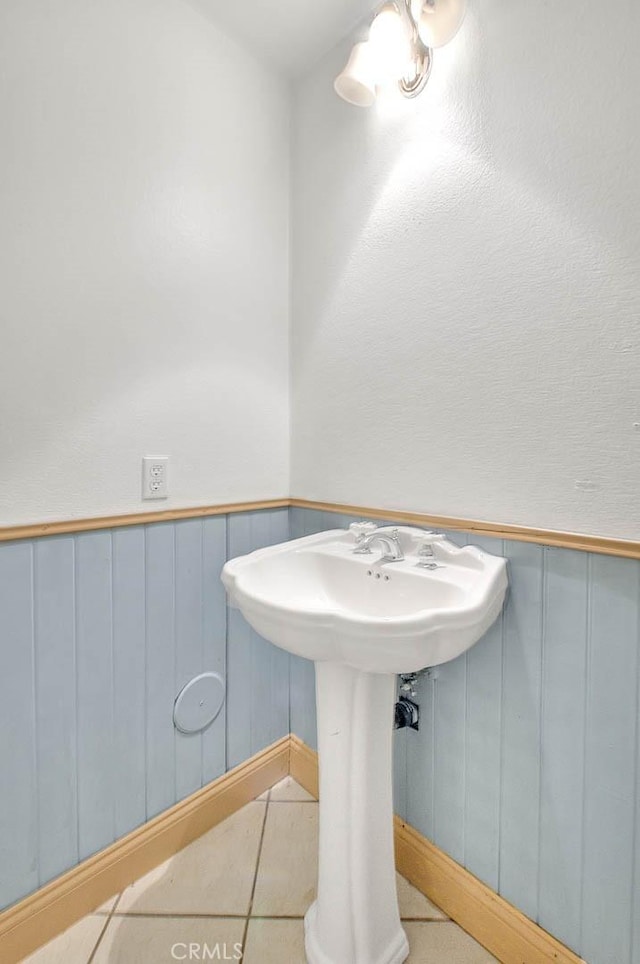 bathroom with tile patterned floors, wood walls, and sink