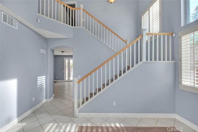 staircase featuring tile patterned flooring and a high ceiling