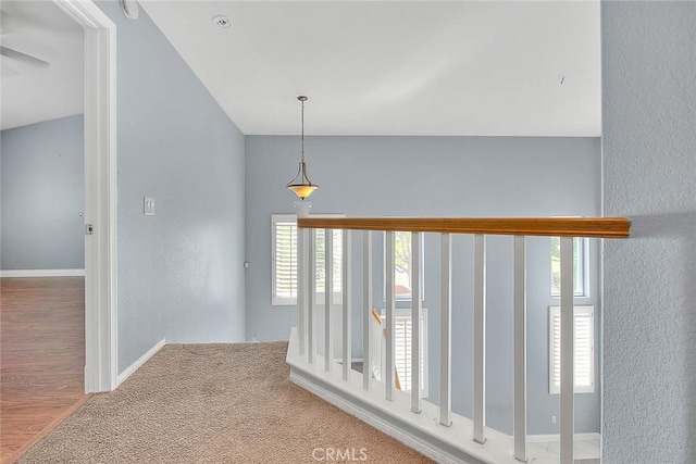 corridor with hardwood / wood-style floors and lofted ceiling