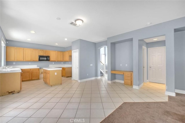 kitchen featuring a kitchen island, built in desk, light tile patterned floors, and light brown cabinetry