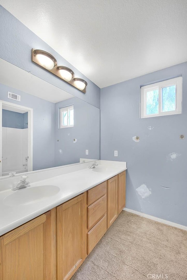 bathroom with a wealth of natural light, vanity, and a textured ceiling