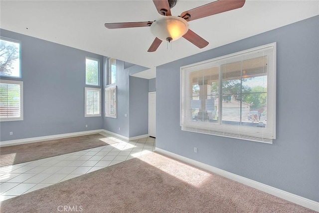 unfurnished room with light colored carpet, a wealth of natural light, and ceiling fan