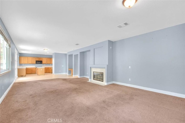 unfurnished living room featuring a high end fireplace and light colored carpet