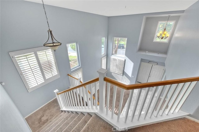 stairway featuring carpet, a towering ceiling, and a notable chandelier