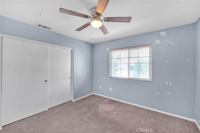 unfurnished bedroom with ceiling fan, a closet, and light colored carpet