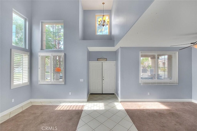 tiled foyer entrance featuring a high ceiling and ceiling fan with notable chandelier