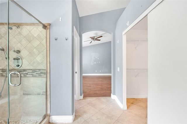 bathroom featuring tile patterned flooring, ceiling fan, lofted ceiling, and a shower with door