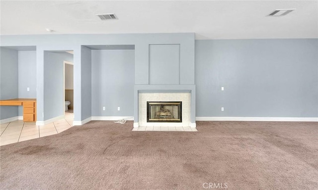 unfurnished living room featuring light carpet and a tiled fireplace