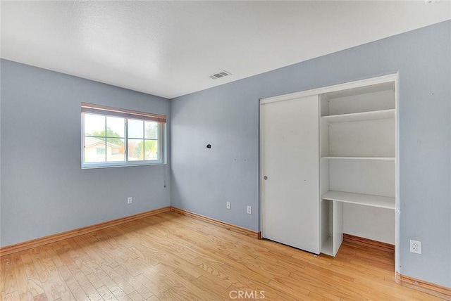 unfurnished bedroom featuring light hardwood / wood-style flooring and a closet